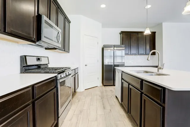 a kitchen with stainless steel appliances granite countertop a sink a stove and a refrigerator