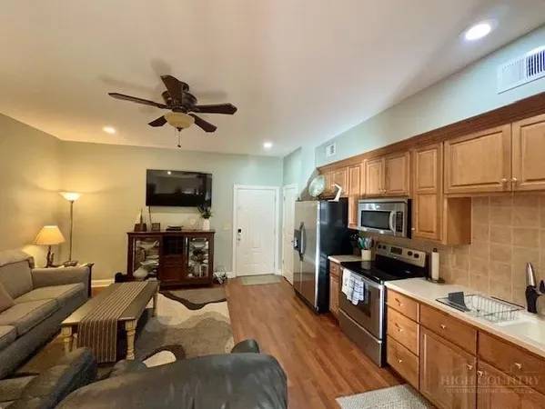 a kitchen with stainless steel appliances a stove a sink a refrigerator a microwave a dining table and chairs with wooden floor