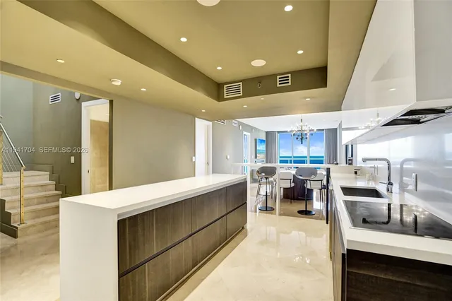 a large kitchen with stainless steel appliances a large counter top a stove and a refrigerator