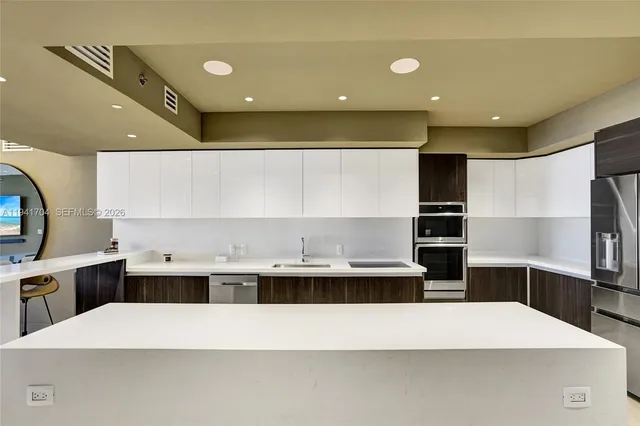 a kitchen with kitchen island a stove a sink a refrigerator and chairs