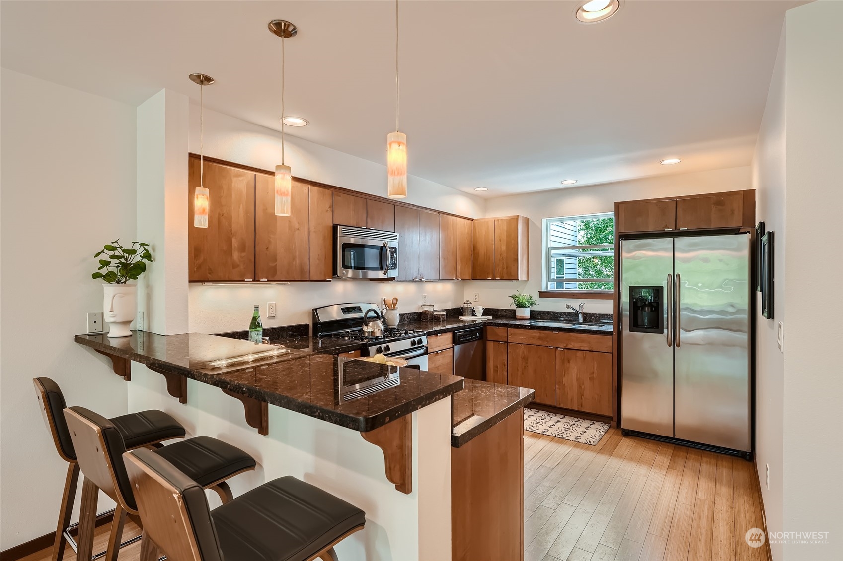 4313 South Webster Street, Unit B Seattle, WA 98118 - Photo 10 of 26 a kitchen with stainless steel appliances granite countertop a refrigerator a sink a stove a dining table and chairs