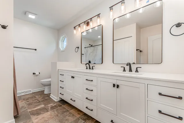 a bathroom with a double vanity sink toilet and a mirror