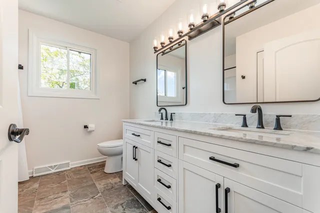 a bathroom with a granite countertop sink mirror and a toilet