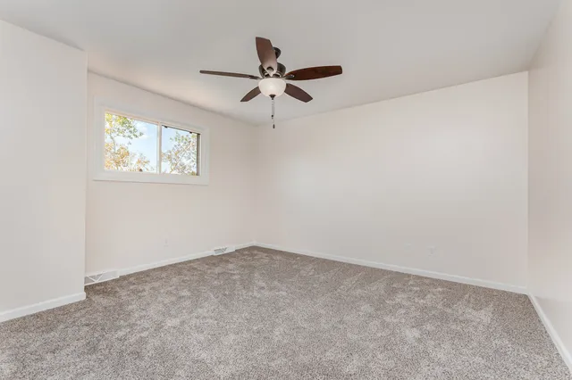 an empty room with a window and a fan