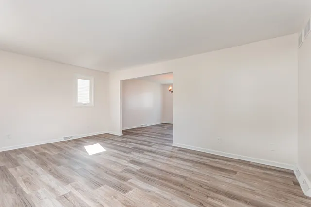 a view of an empty room with wooden floor and closet