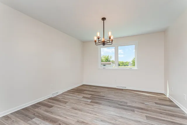 a view of empty room with window and wooden floor