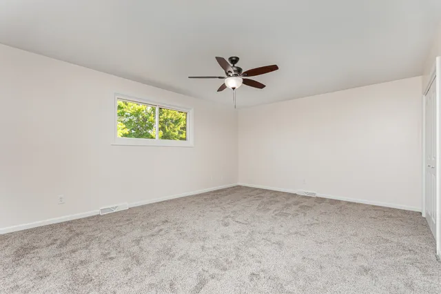 an empty room with a window and a fan