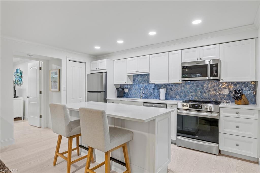 960 7th Street South, Unit 101 Naples, FL 34102 - Photo 4 of 11 a kitchen with stainless steel appliances granite countertop a stove a sink and a refrigerator