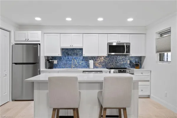 a kitchen with stainless steel appliances granite countertop a refrigerator a stove a microwave a sink and white cabinets