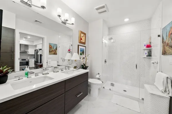 a bathroom with a double vanity sink toilet mirror and shower