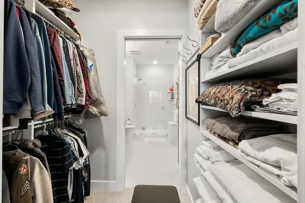 a view of walk in closet with clothes and shoes