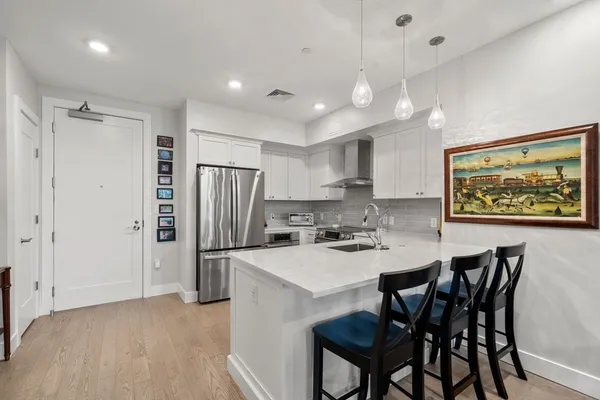 a kitchen with stainless steel appliances granite countertop a refrigerator a sink a stove a dining table and chairs