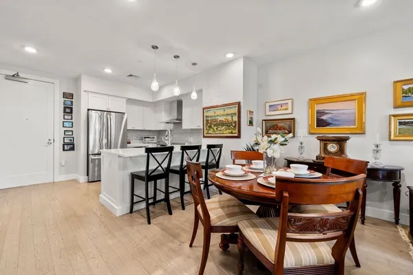 a dining room with stainless steel appliances kitchen island granite countertop a dining table chairs and a refrigerator