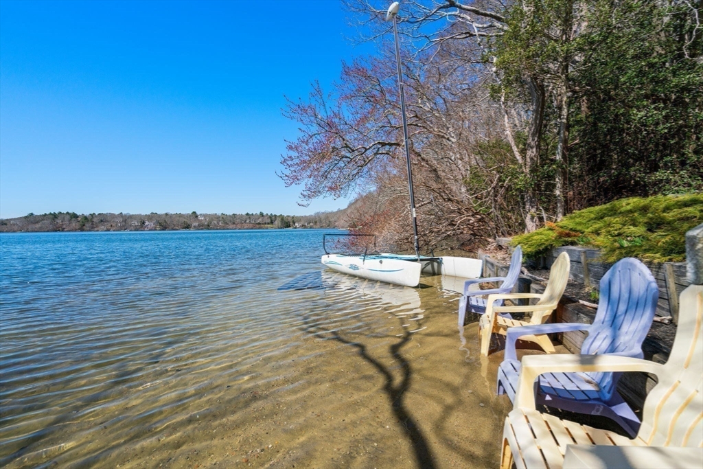 130 Pimlico Pond Road Mashpee, MA 02649 - Photo 3 of 39 a view of a patio with lawn chairs under an umbrella