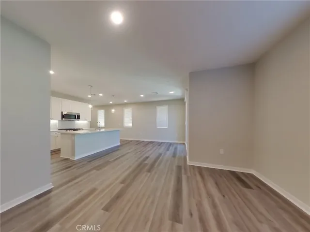 a view of kitchen and empty room with wooden floor