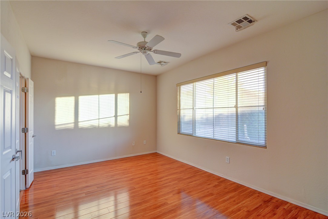2339 Tranquil Moon Street Henderson, NV 89044 - Photo 6 of 15 Warm wood flooring grounds this versatile bedroom featuring generous windows and clean lines.