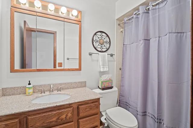a bathroom with a granite countertop toilet a sink and a mirror