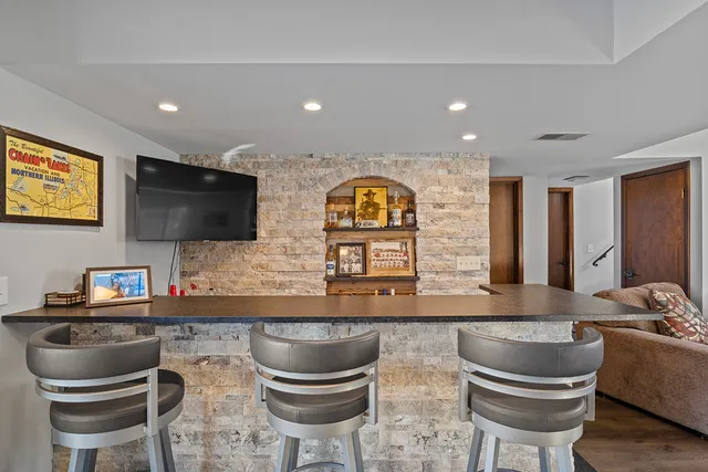 a kitchen with stainless steel appliances granite countertop a stove a sink and a flat screen tv