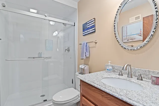 a bathroom with a granite countertop sink toilet a mirror and shower