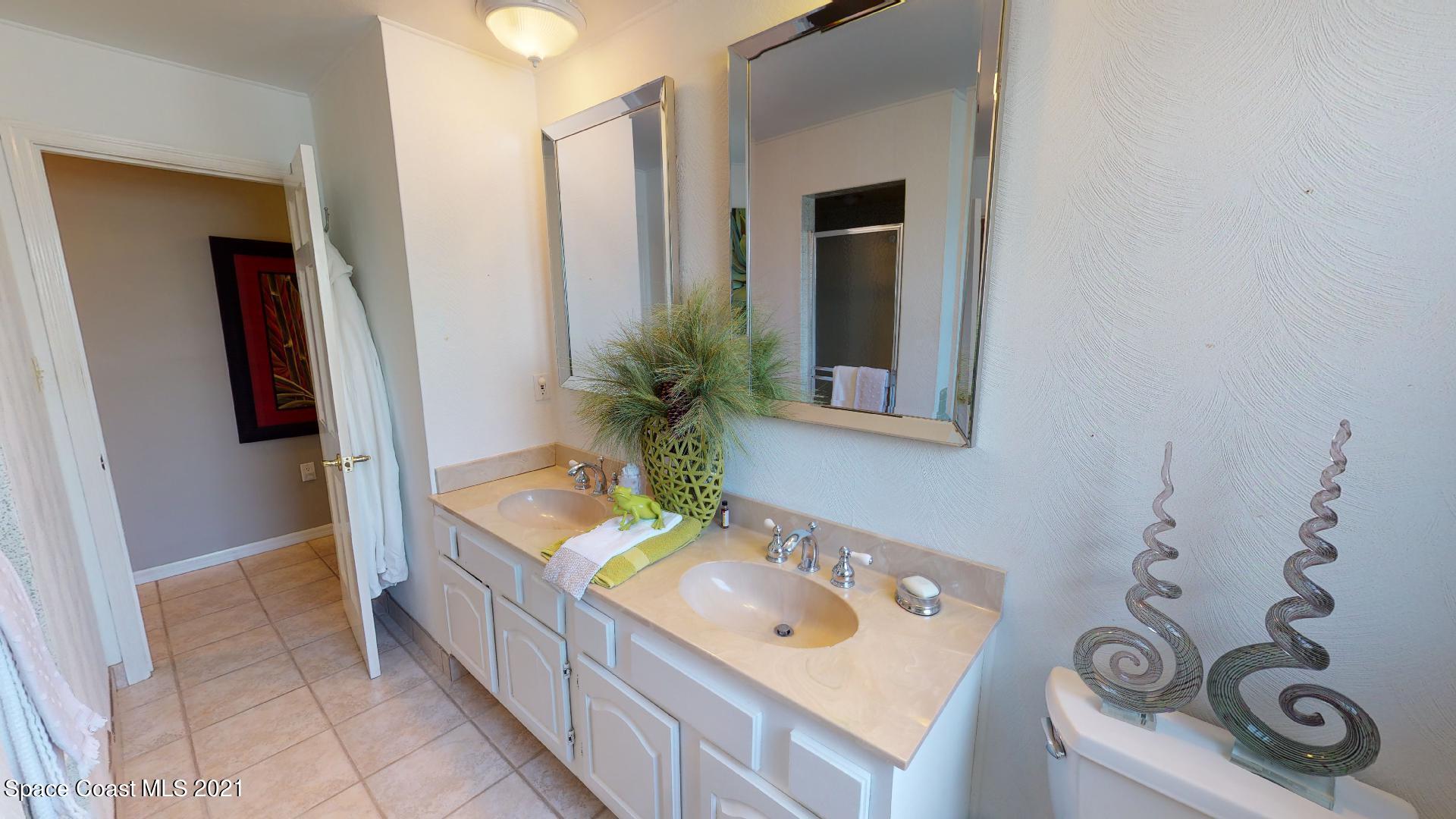 61 Country Club Road Cocoa Beach, FL 32931 - Photo 42 of 100 a bathroom with a sink a mirror and shower