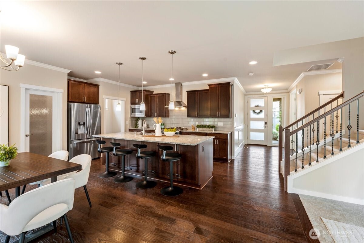 11 200th Place Southwest Bothell, WA 98012 - Photo 16 of 40 a kitchen with stainless steel appliances a stove a refrigerator a kitchen island a dining table and chairs with wooden floor