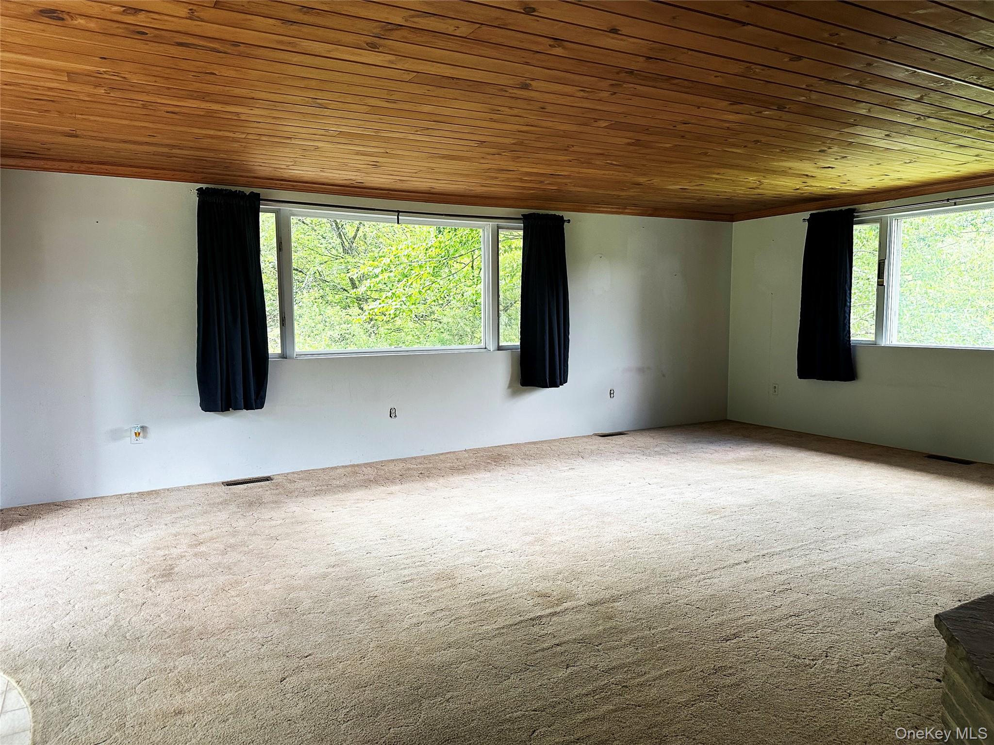 818 Methol Road Roscoe, NY 12776 - Photo 25 of 39 Expansive living area with oversized windows overlooking the surrounding greenery, complemented by original wood ceilings and rustic finishes throughout.