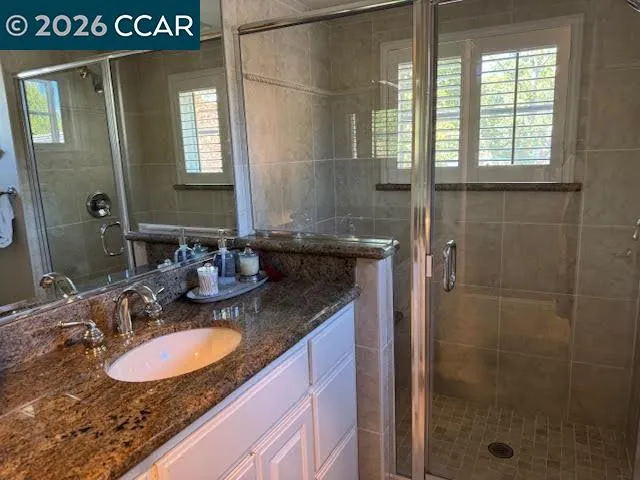 a bathroom with a granite countertop sink a mirror and a shower