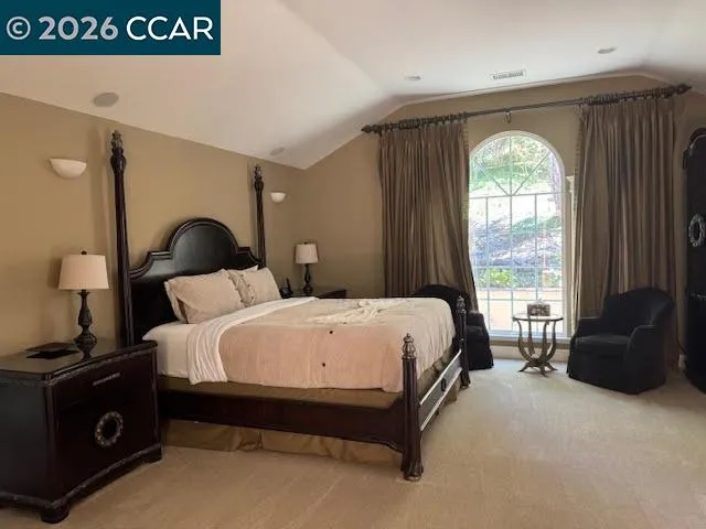 a bed sitting in a spacious bedroom next to a window