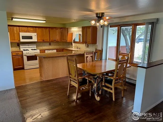 a kitchen with stainless steel appliances kitchen island granite countertop a stove top oven a sink a dining table and chairs with wooden floor