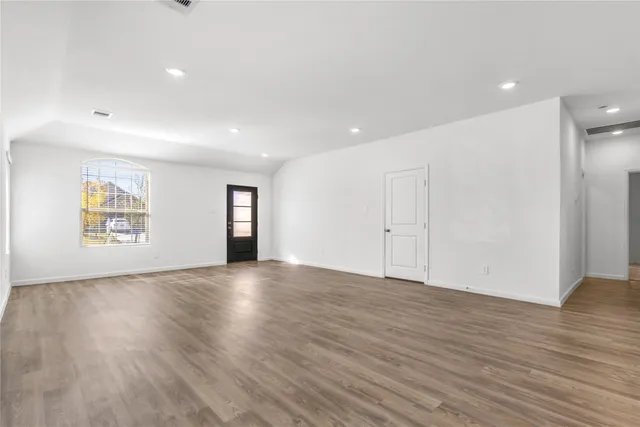 a view of an empty room with wooden floor and window