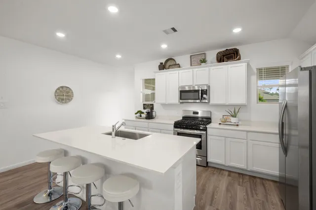 a kitchen with granite countertop a sink stove and refrigerator