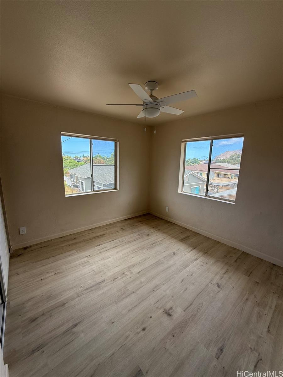 85-808 Lihue Street, Unit UPPR Waianae, HI 96792 - Photo 11 of 19 an empty room with wooden floor chandelier and windows