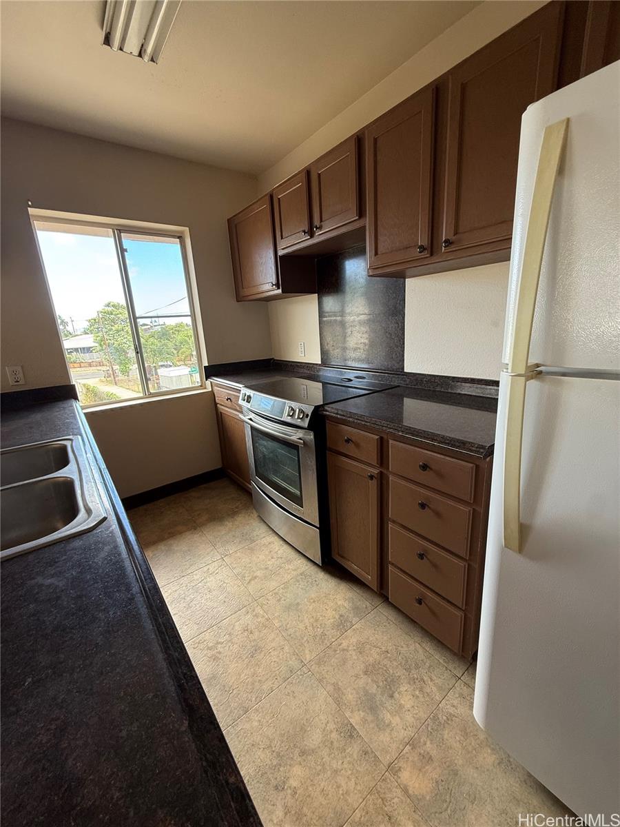 85-808 Lihue Street, Unit UPPR Waianae, HI 96792 - Photo 6 of 19 a kitchen with stainless steel appliances granite countertop a stove a refrigerator and a sink