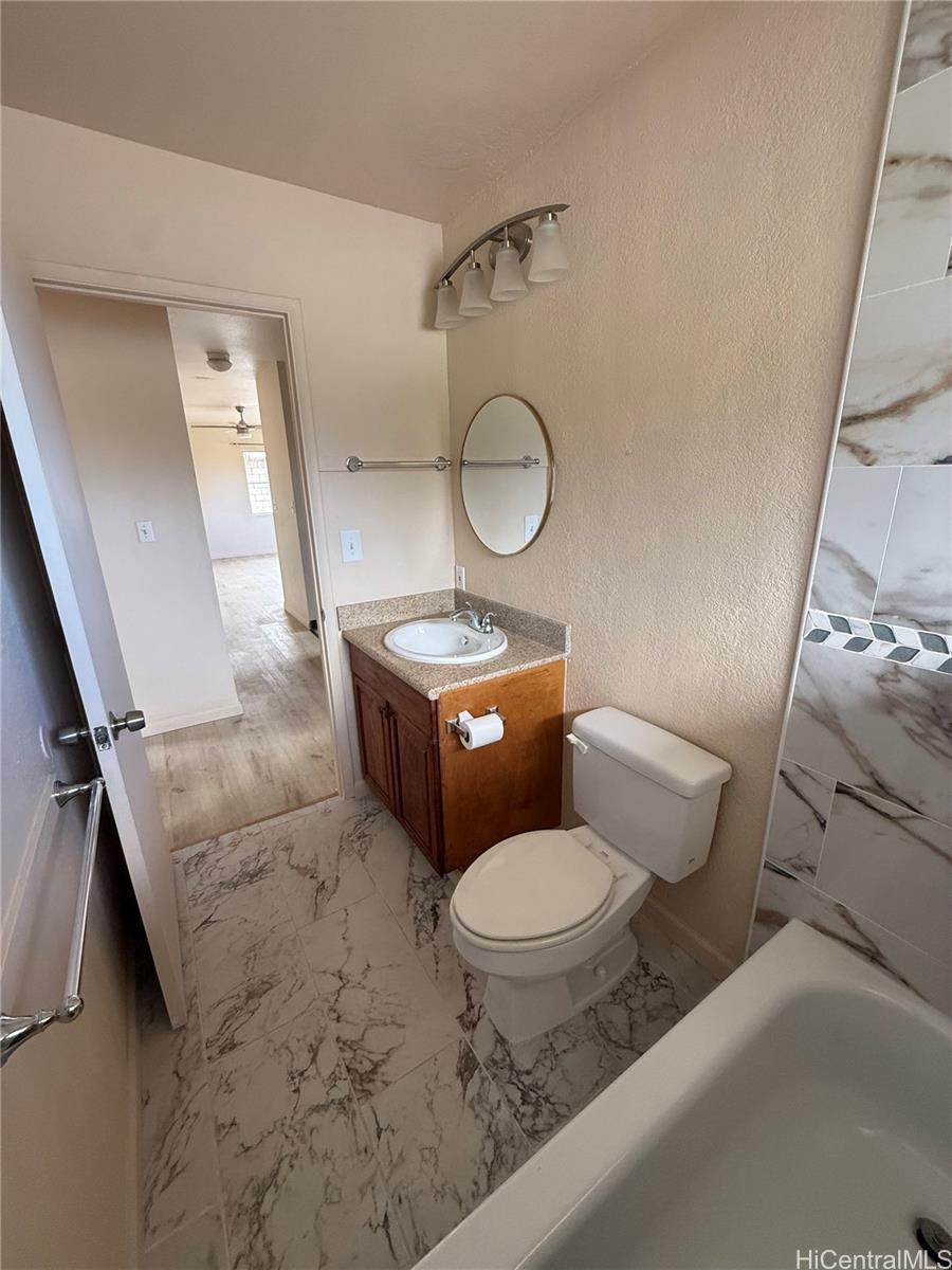 85-808 Lihue Street, Unit UPPR Waianae, HI 96792 - Photo 9 of 19 a bathroom with a toilet sink mirror vanity and toilet
