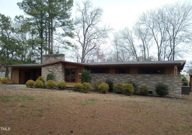 a view of a house with a yard and large tree