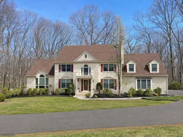 a view of a white house next to a yard with big trees