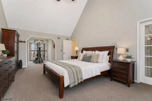 a spacious bedroom with a bed and a flat tv screen on dresser