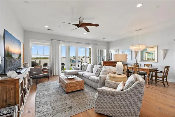 a living room with furniture floor to ceiling window and wooden floor