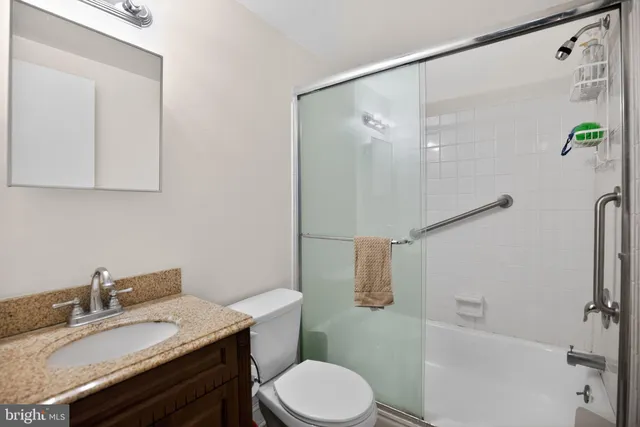 a bathroom with a granite countertop sink toilet a mirror and shower