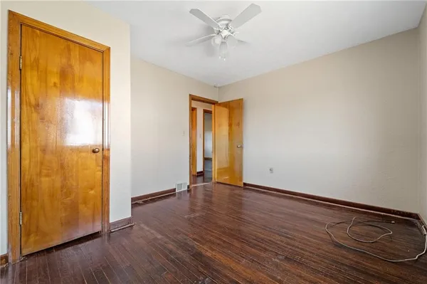 an empty room with wooden floor and a ceiling fan