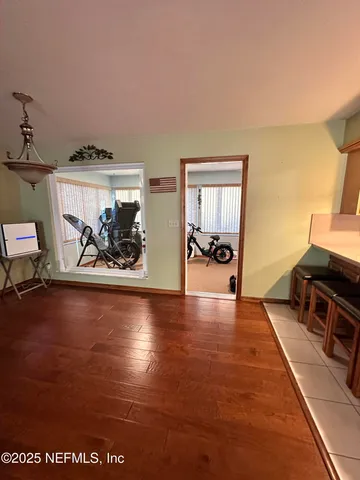 a view of a room with gym equipment and wooden floor