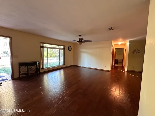 an empty room with wooden floor and windows