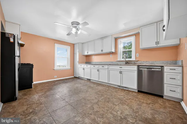 a kitchen with stainless steel appliances a sink a stove a refrigerator cabinets and a window