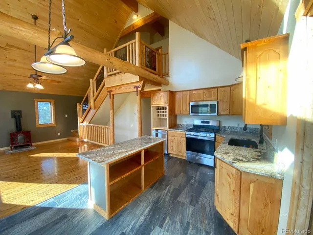 a kitchen with stainless steel appliances granite countertop a sink a stove and a wooden floors