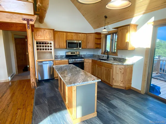 a kitchen with stainless steel appliances granite countertop a stove top oven a sink dishwasher and wooden cabinets with wooden floor