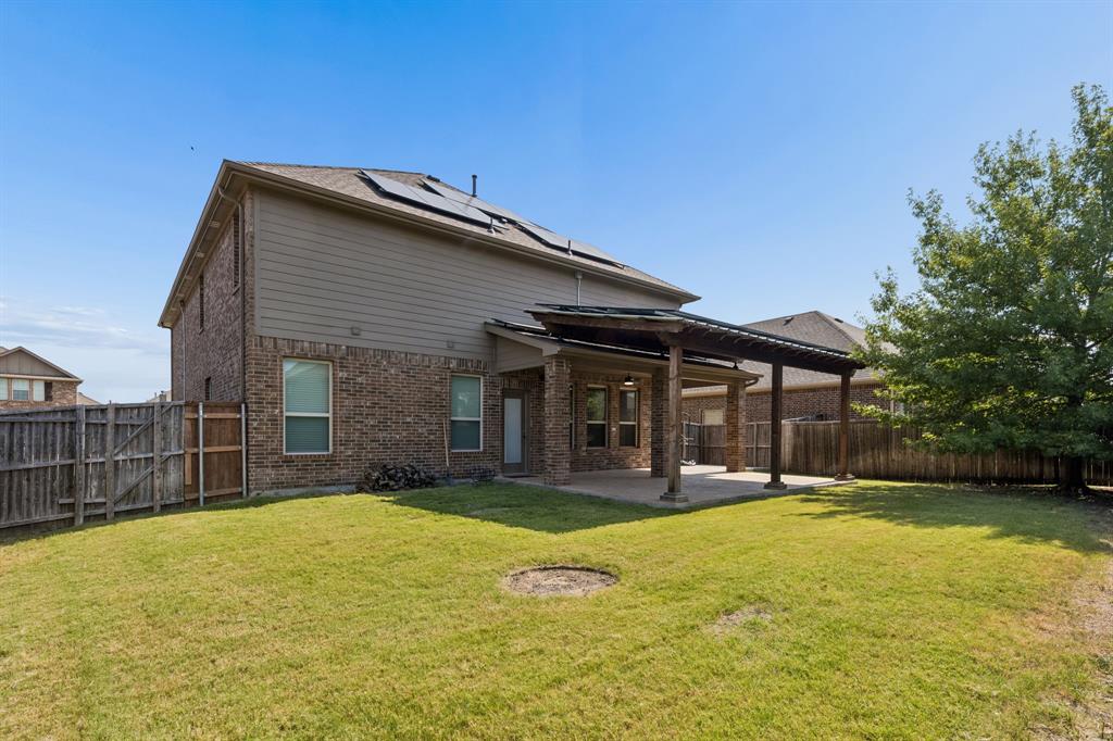 537 Hunt Farms Road Fate, TX 75189 - Photo 34 of 36 Expansive backyard featuring a covered patio, brick exterior, solar panels, and a wood privacy fence