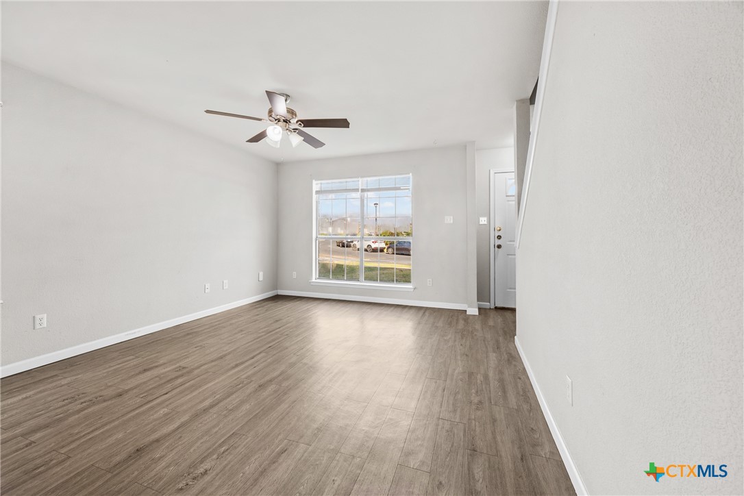 2117 Schwald Road Killeen, TX 76543 - Photo 4 of 29 an empty room with wooden floor ceiling fan and windows