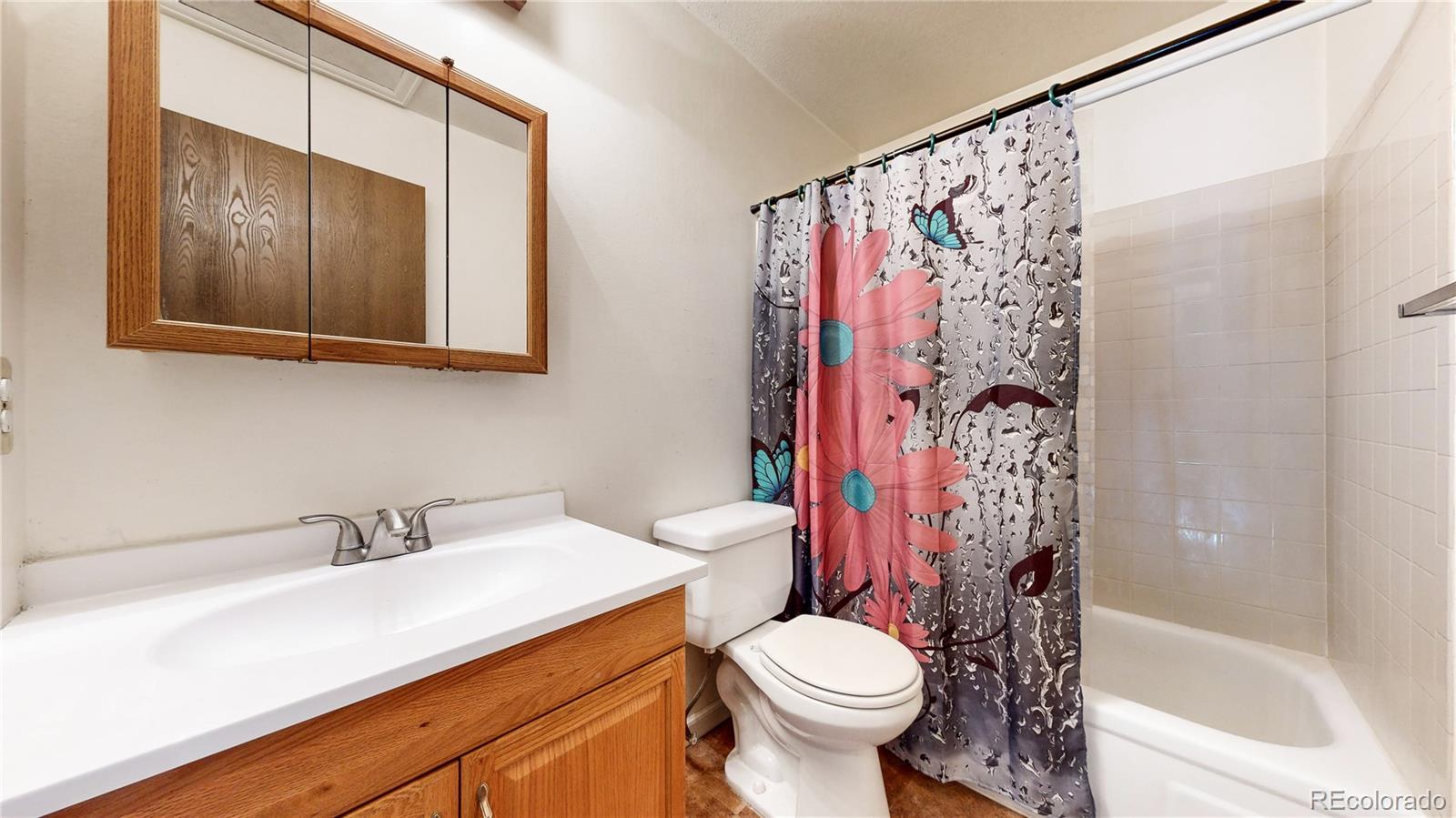 8906 Everett Street Broomfield, CO 80021 - Photo 17 of 35 a bathroom with a sink a toilet and shower curtain