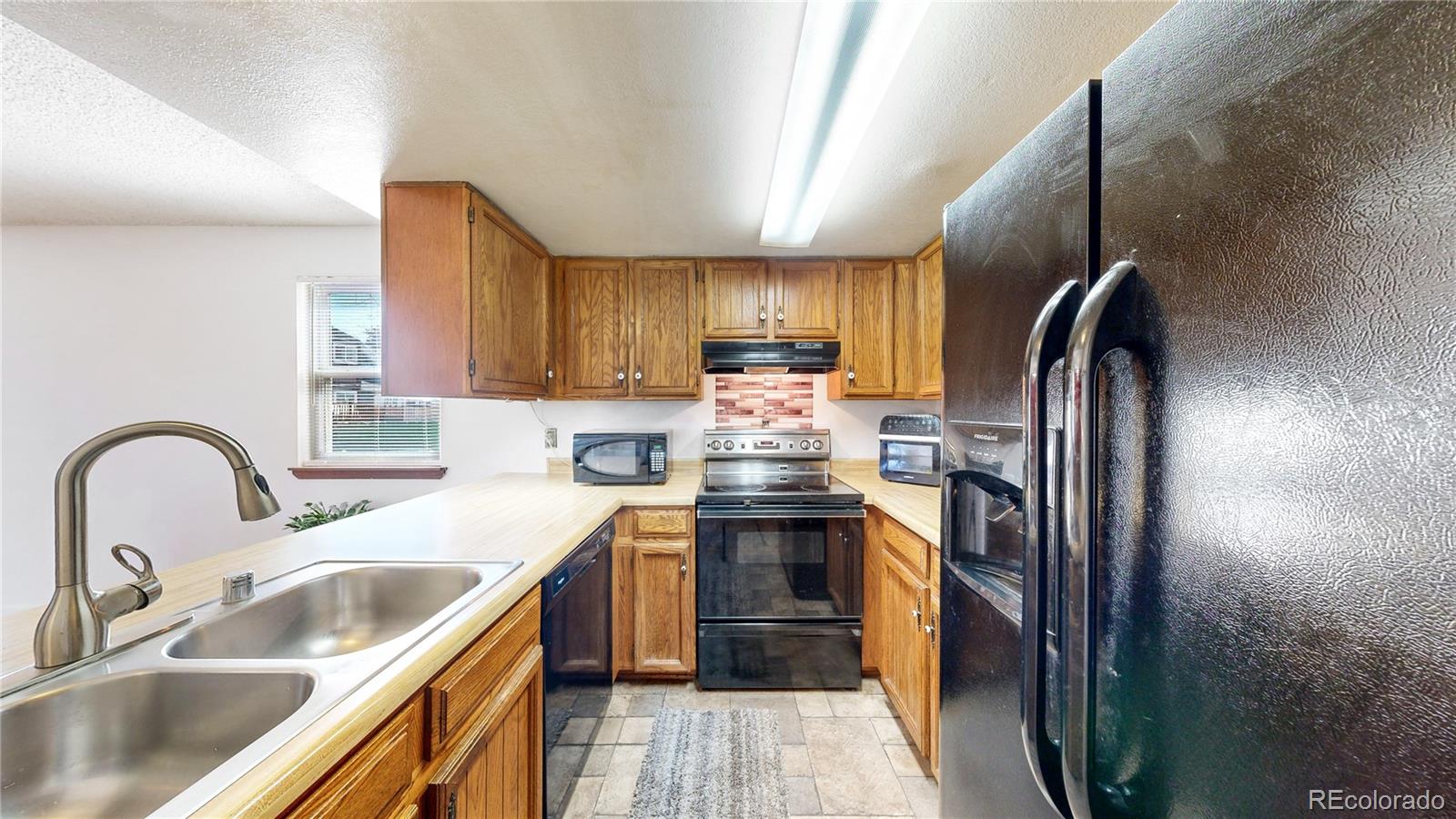 8906 Everett Street Broomfield, CO 80021 - Photo 8 of 35 a kitchen with stainless steel appliances granite countertop a sink stove and refrigerator