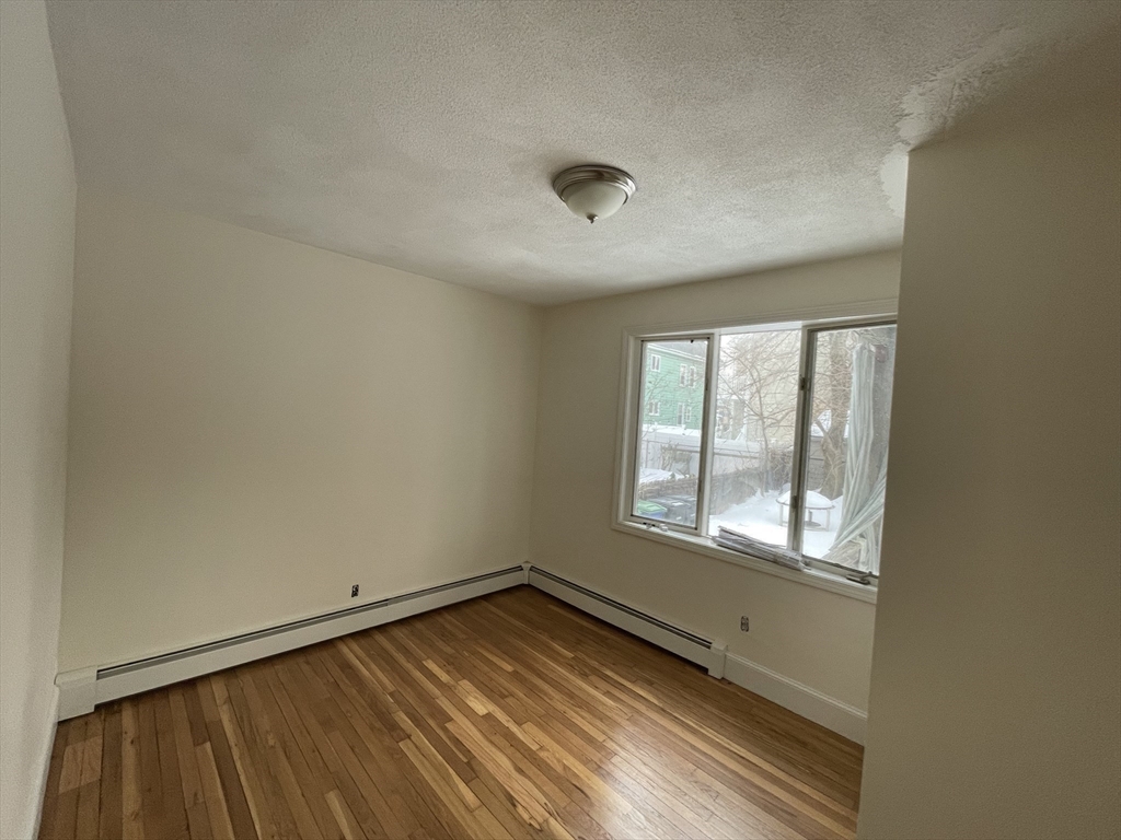 26-28 Adrian Street Somerville, MA 02143 - Photo 15 of 32 an empty room with wooden floor and windows